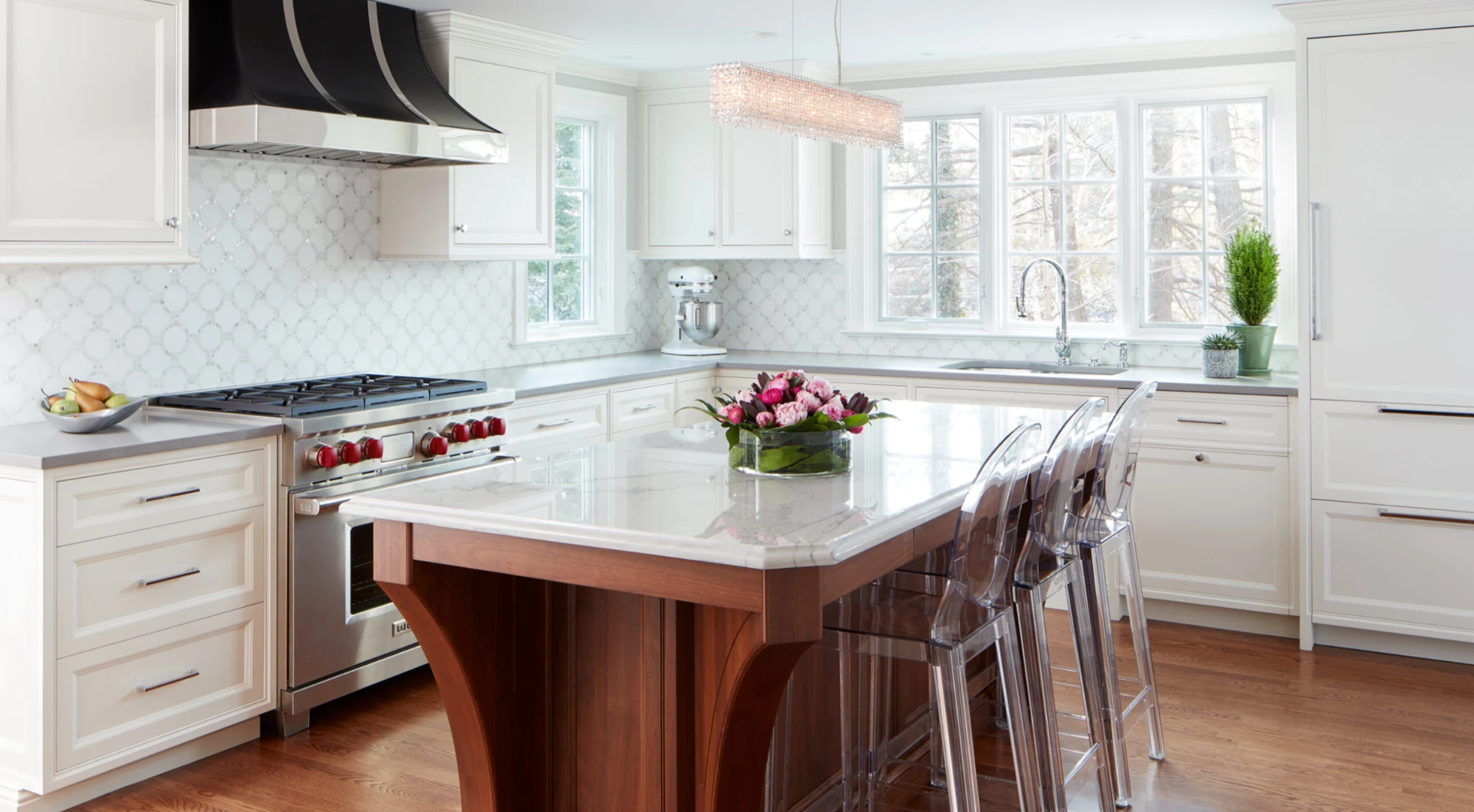 Light-filled New England kitchen with white cabinetry, a walnut island, stone counters, and a sculptural range hood