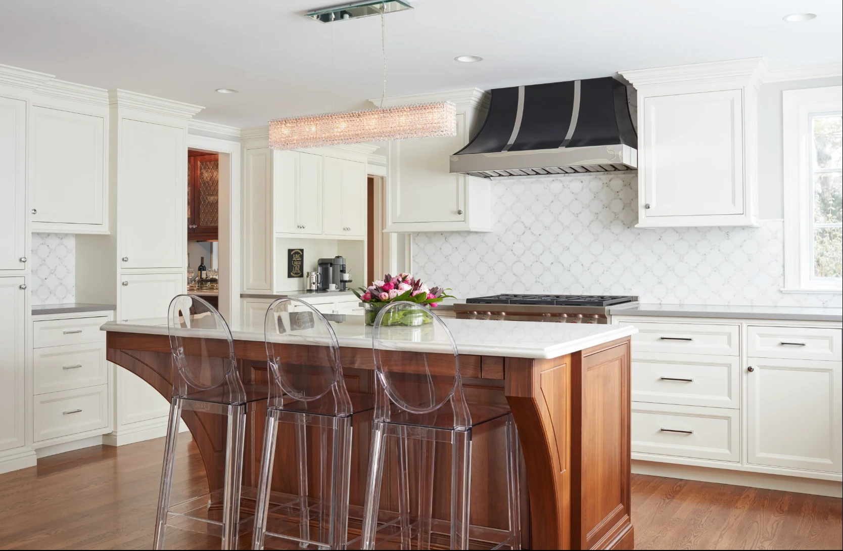 White kitchen cabinetry and walnut island with transparent seating